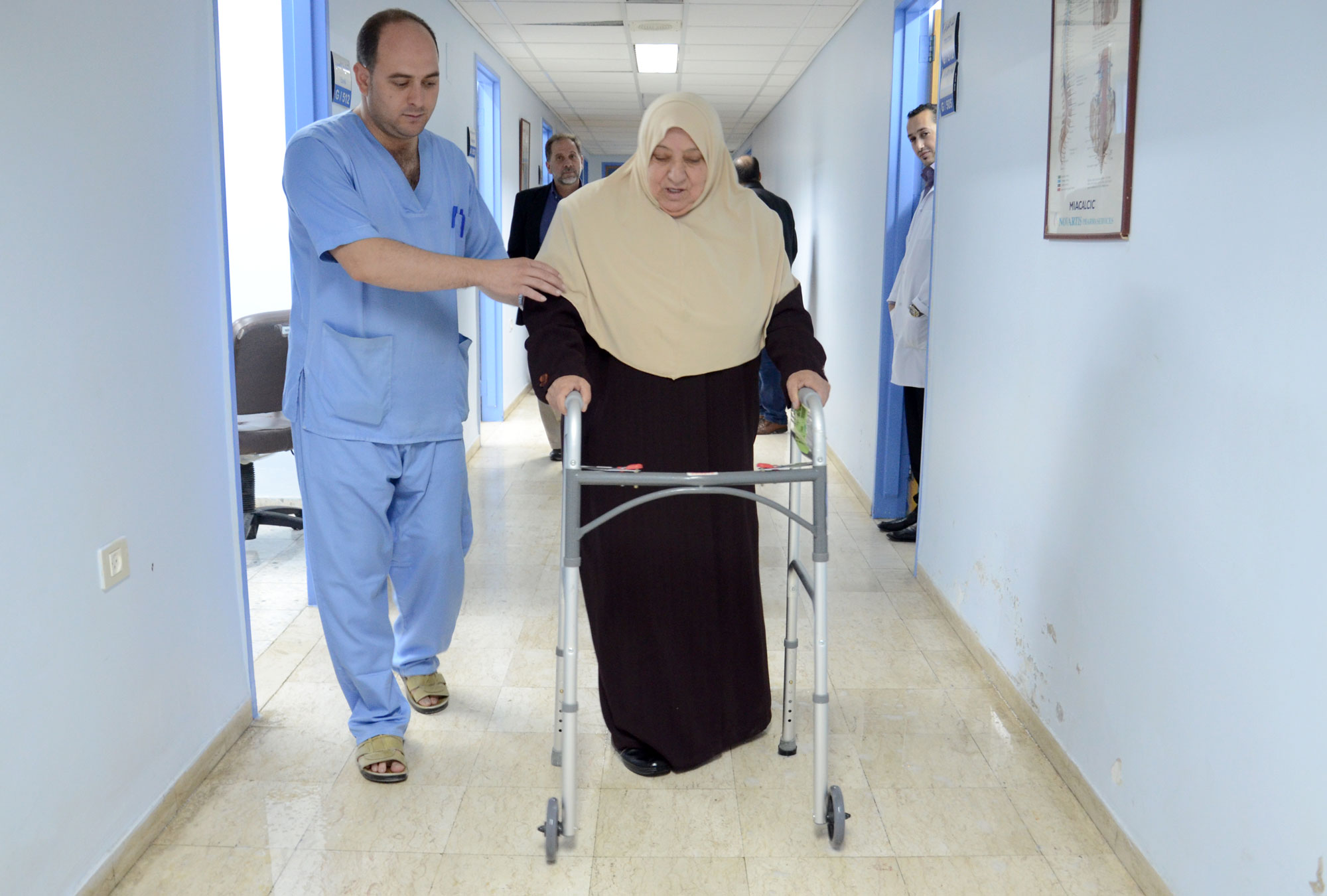 Maliha takes a walk down hospital hallway n Hebron with hew new walker from Anera.