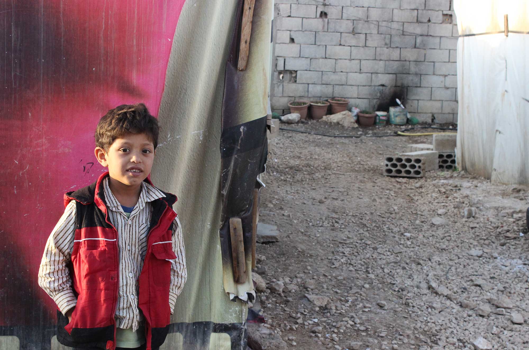 A Syrian boy stands outside his tented home in a Bekaa Valley settlement known as Zahle 601. ©Niki Erickson, November 2015.