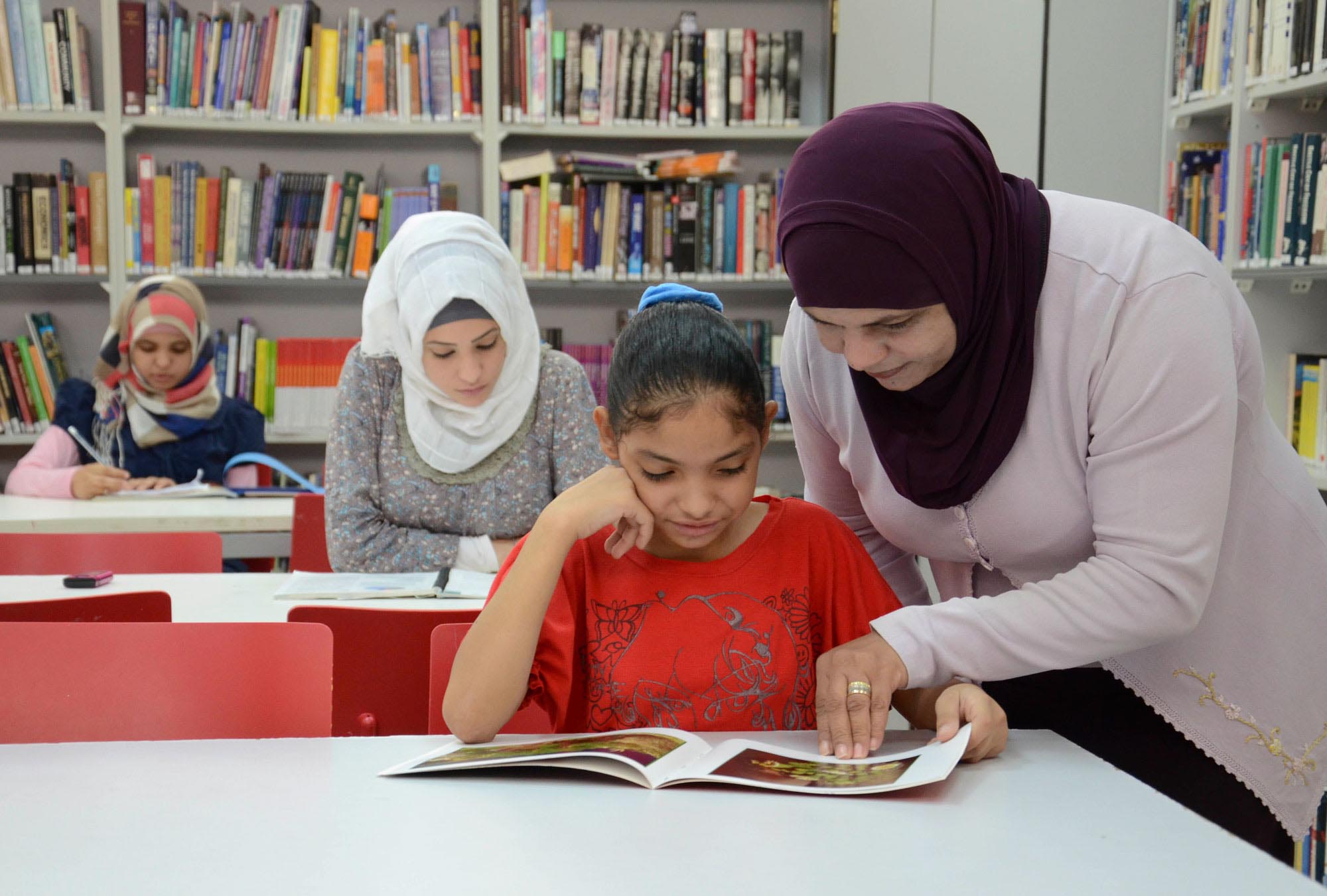 Head Librarian May Hilal shows a reader some interesting information in one of the 30,000 books housed in the Jericho library Anera built in 2005.