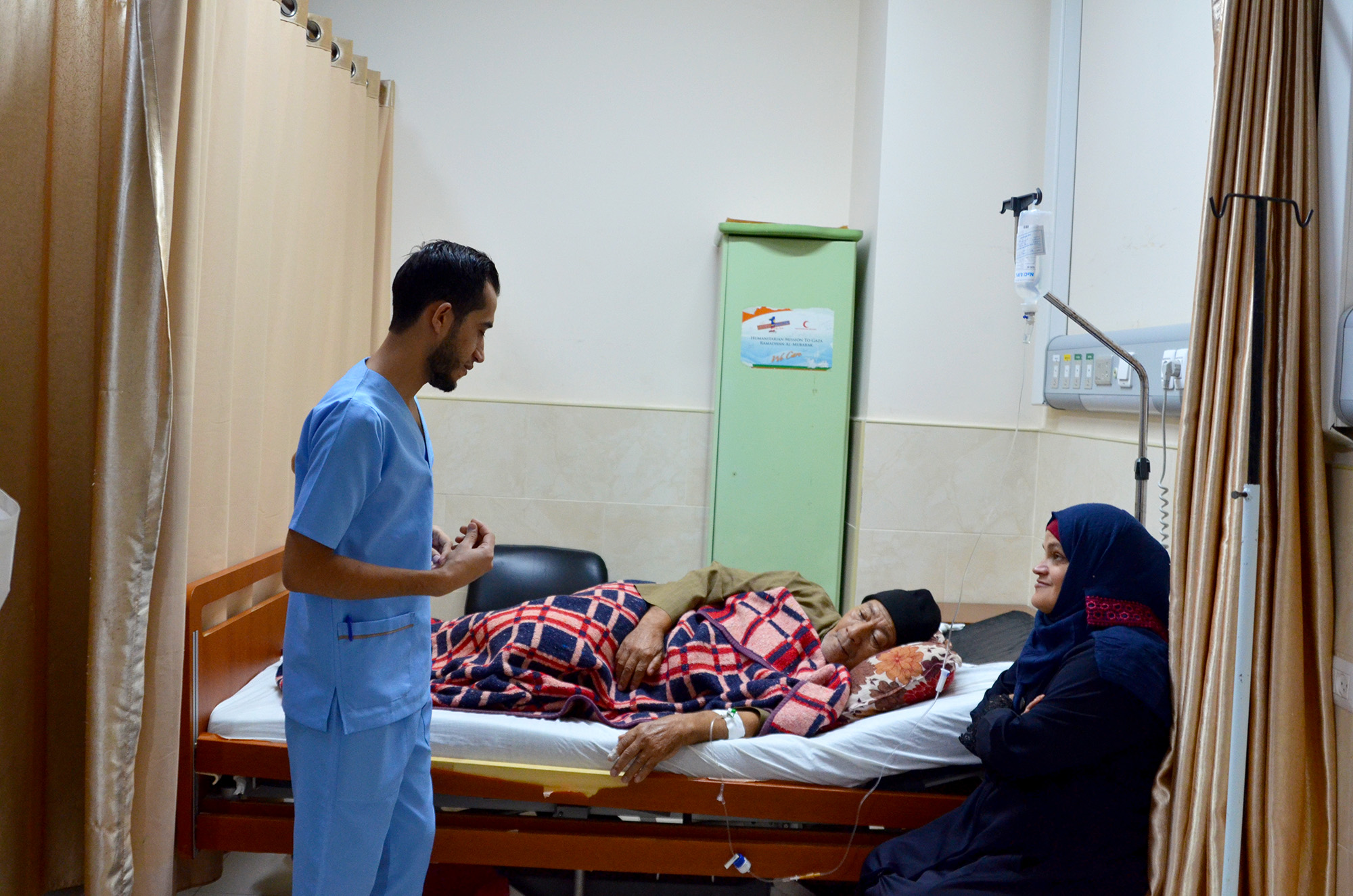 Omar by the bedside of his father Azaam at Al Quds Hospital in Gaza.