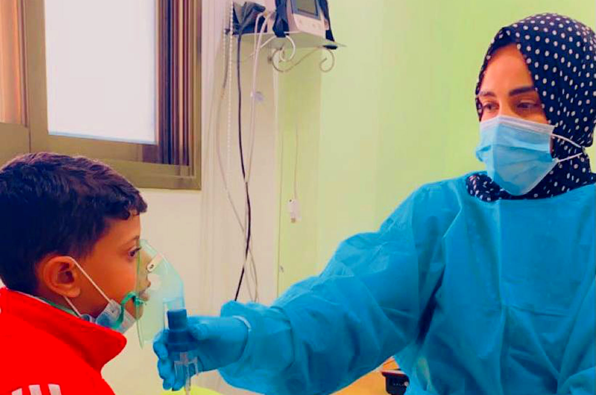 A nurse holds the nebulizer mask to Yaseen's face.