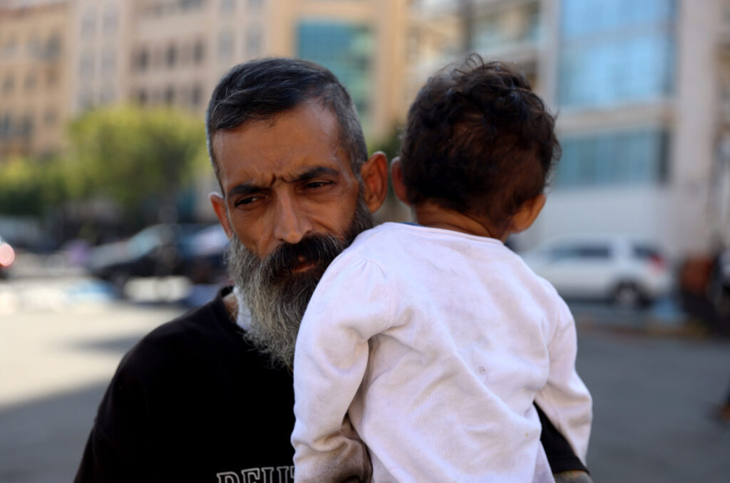 Abu, displaced from Syria, carries his son in Beirut after being displaced to the street once again.