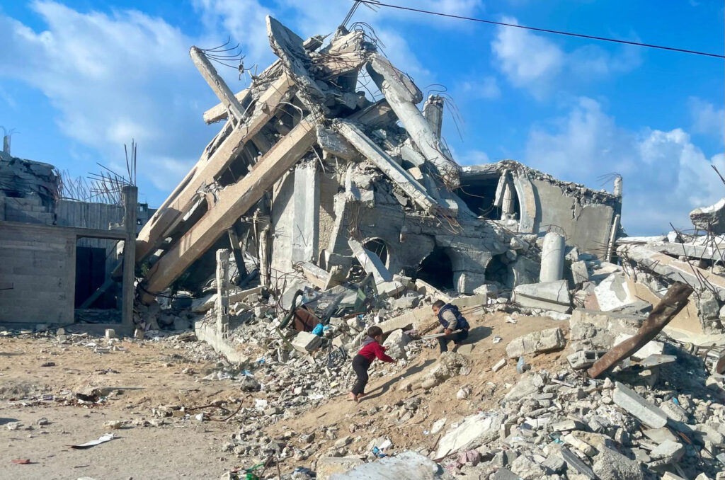 Destroyed building in Gaza with children playing in the rubble.